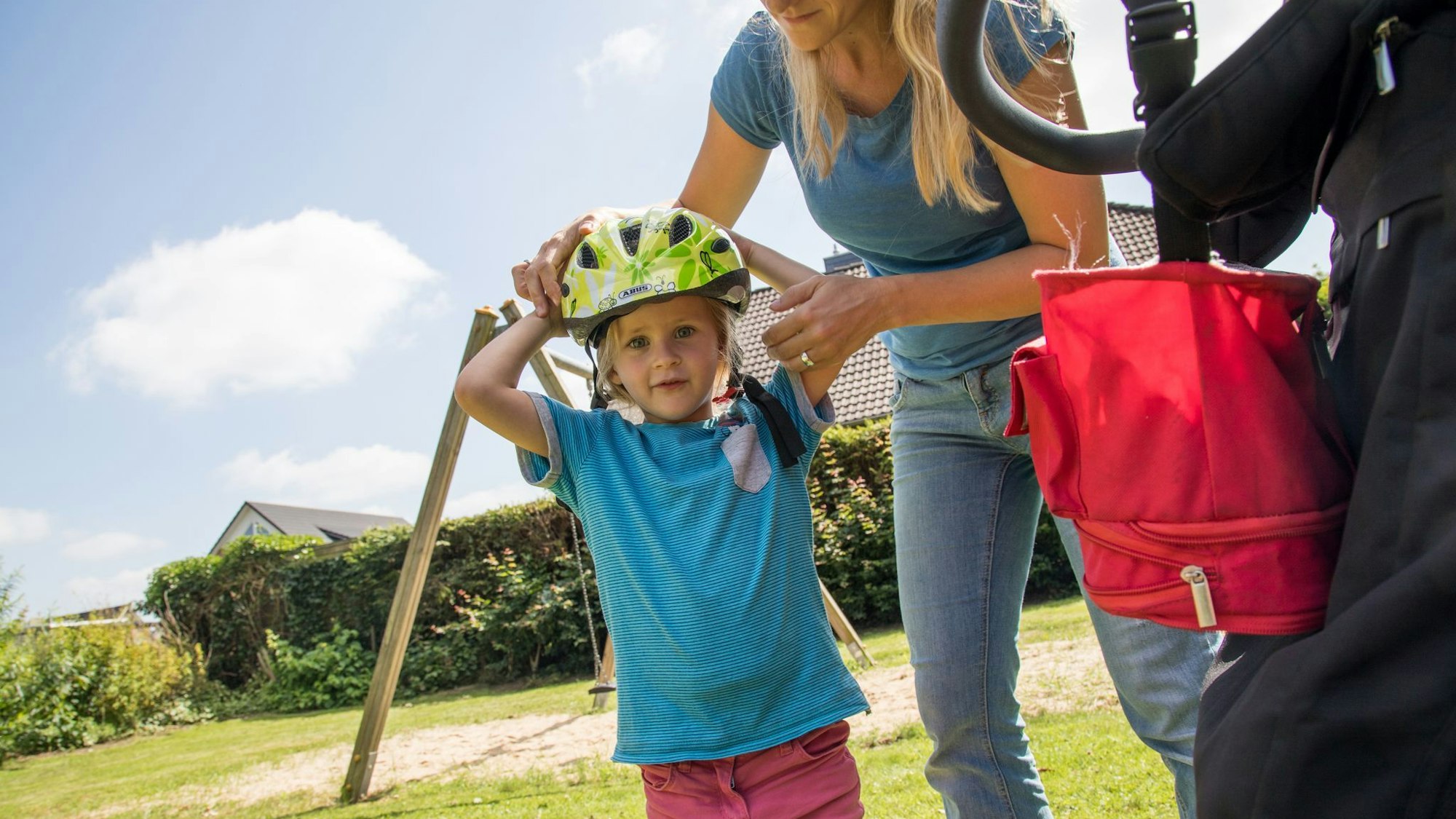 Eine Frau setzt ihrem Kind einen Fahrradhelm auf