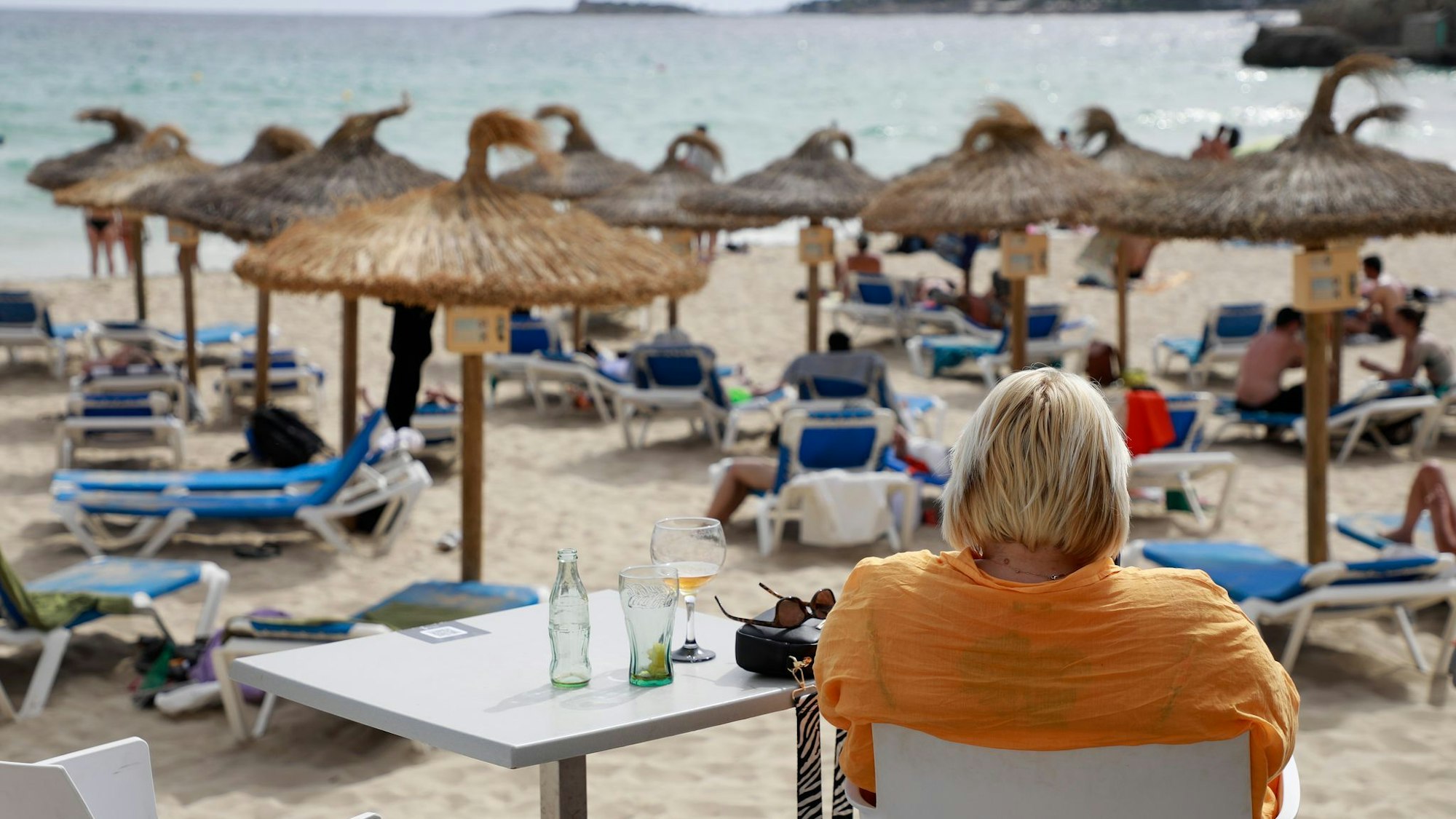 Frau sitzt am Strand von Cala Major in einem Café