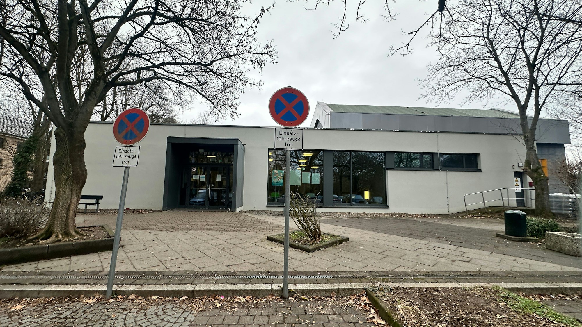 Vor einem Flachbau stehen zwei Parkhinweisschilder.