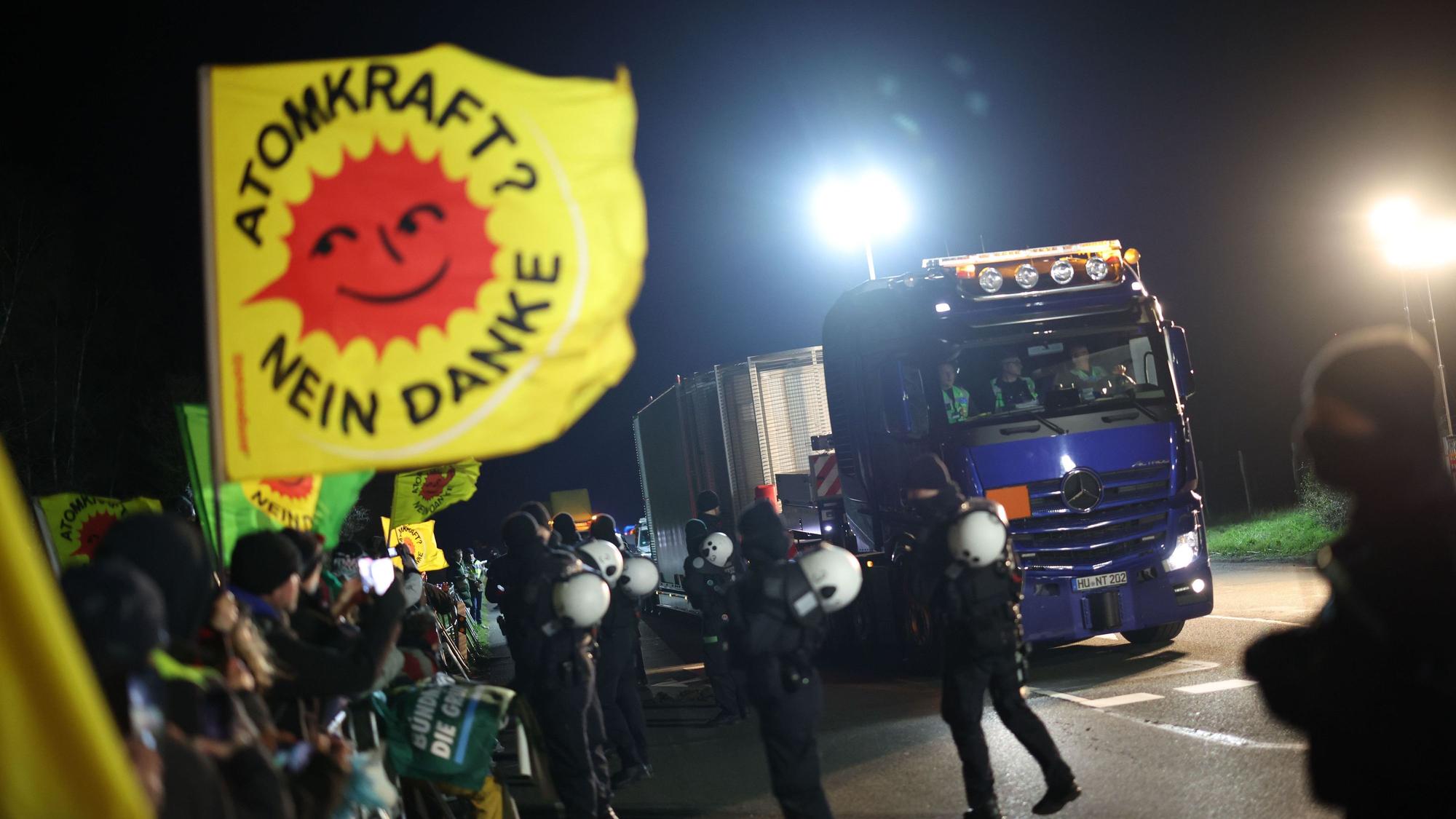 Ein Schwertransporter mit einem Castor-Behälter fährt an Teilnehmern einer Anti-Atomkraft-Demonstration vorbei, die entlang der Strecke bei Ahaus gegen die Castor-Transporte protestieren.