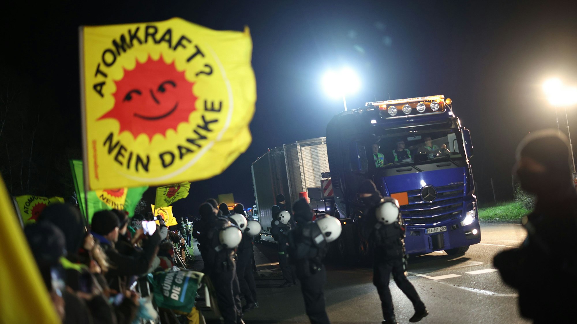 Ein Schwertransporter mit einem Castor-Behälter fährt an Teilnehmern einer Anti-Atomkraft-Demonstration vorbei, die entlang der Strecke bei Ahaus gegen die Castor-Transporte protestieren.