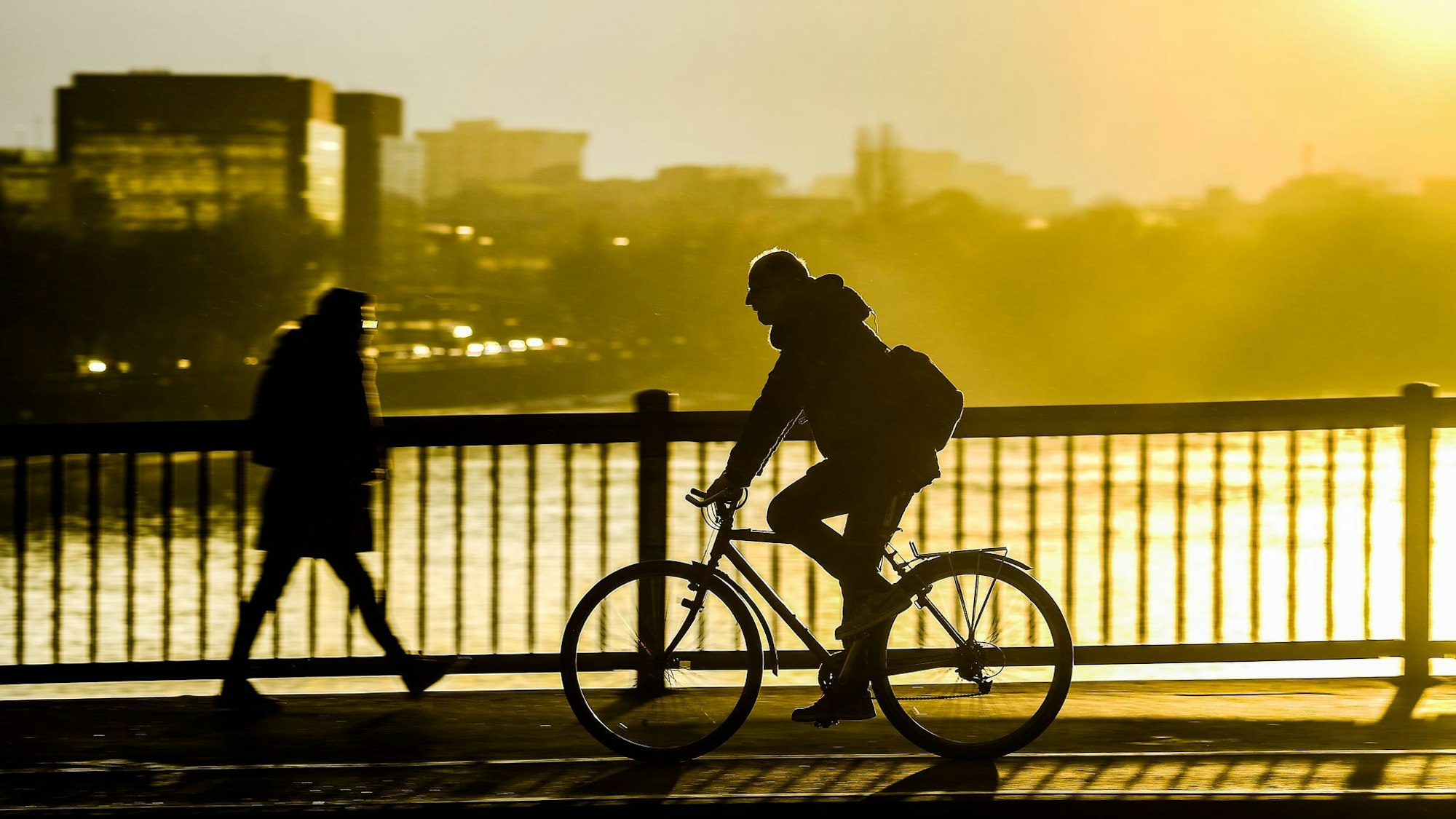 Fahrradfahrer fährt im Sonnenuntergang über eine Brücke