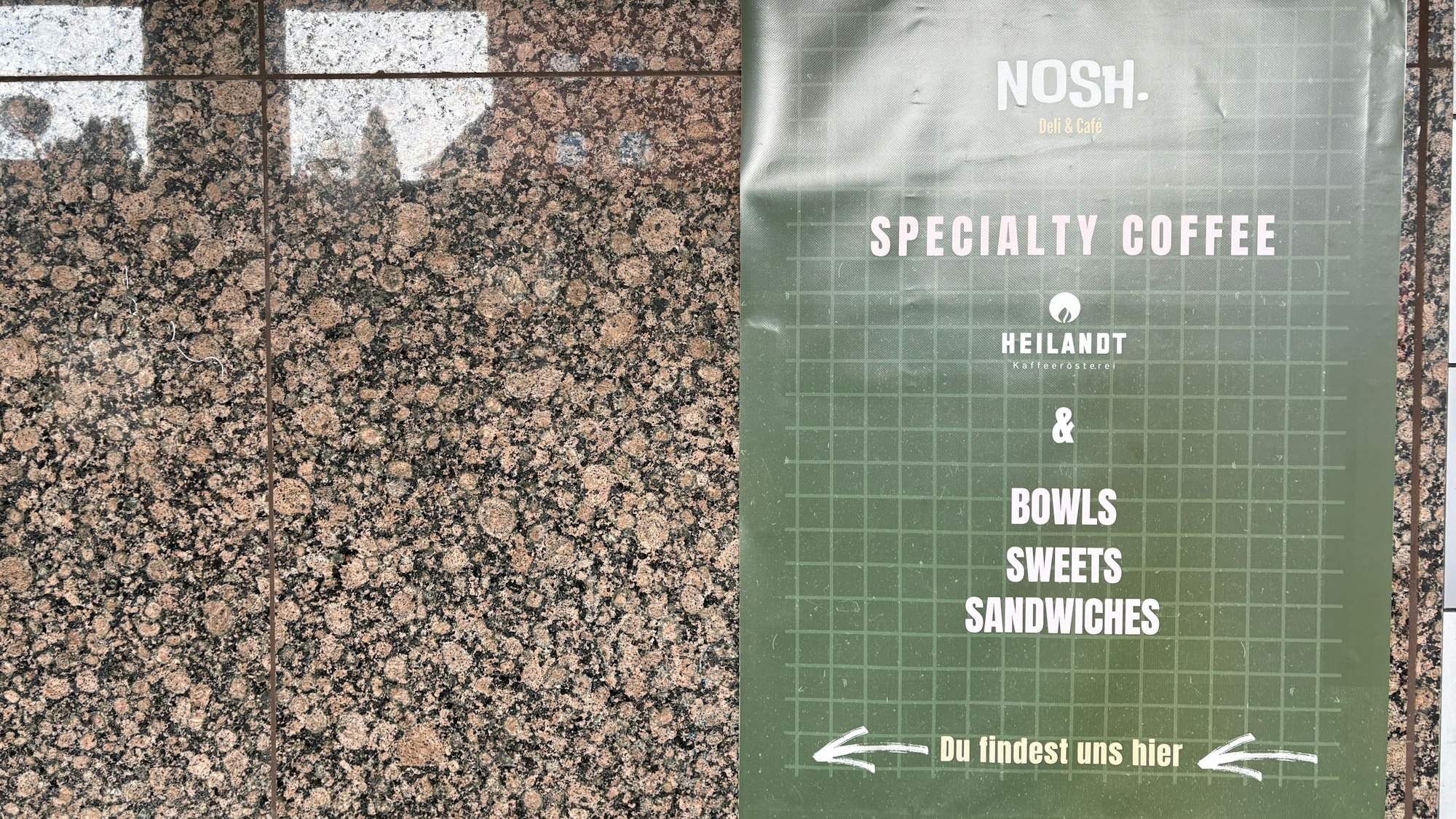 Das Poster des Delis, denn es liegt etwas versteckt hinter einem Bauzaun.