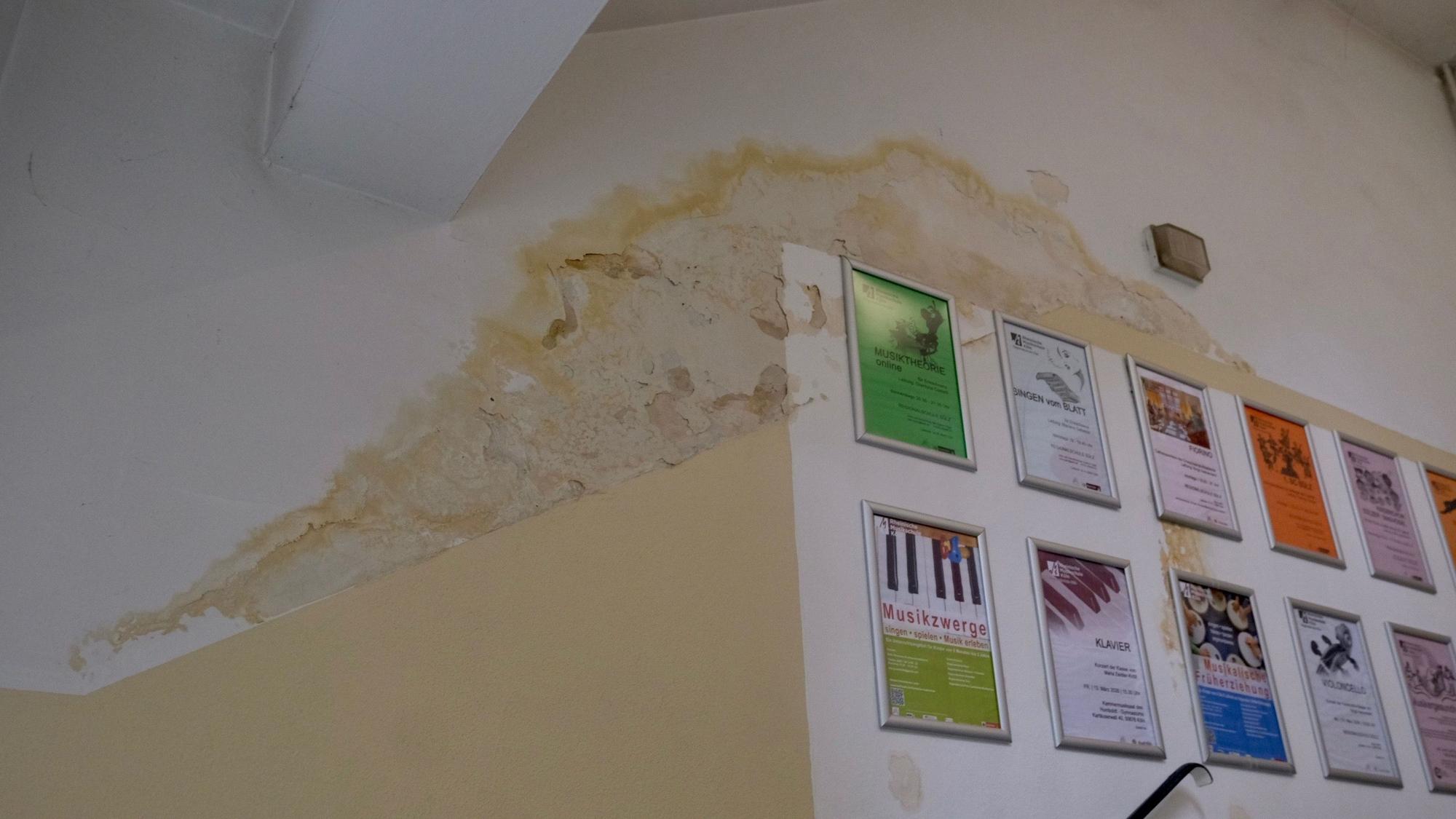 Ein Wasserschaden zeichnet sich an einer Decke und Wand eines Gebäudes ab.