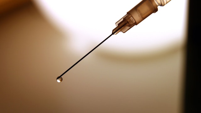 Eine Flüssigkeit tropft aus der Kanüle einer Spritze