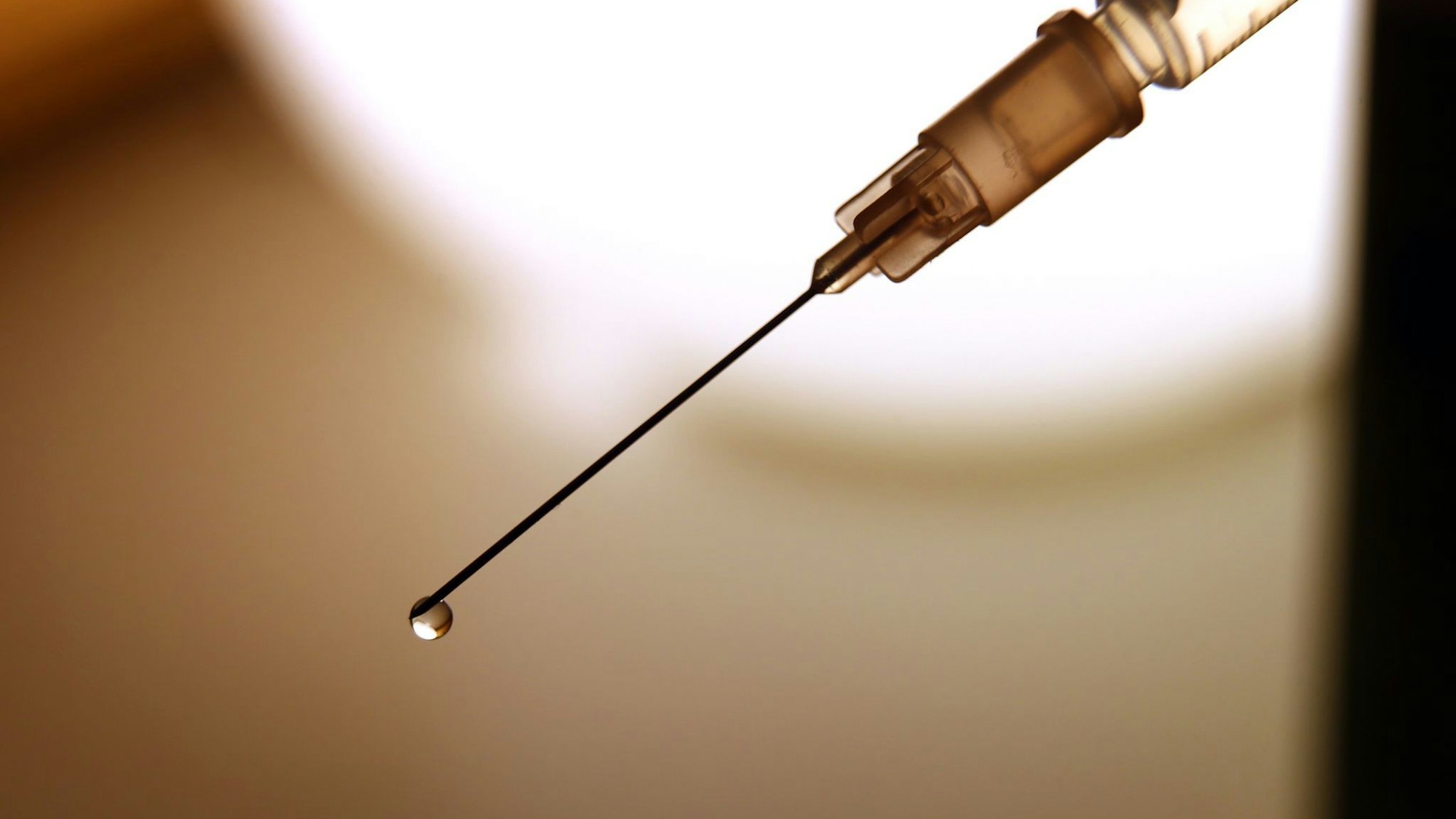 Eine Flüssigkeit tropft aus der Kanüle einer Spritze