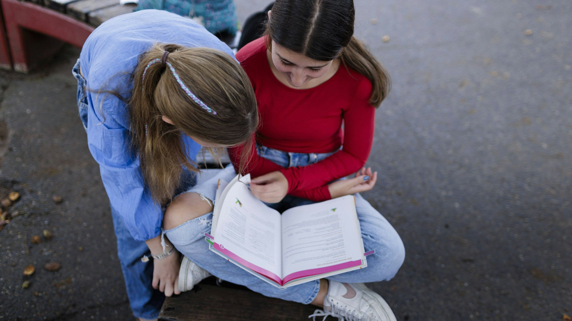 Zwei Mädchen sitzen auf einem Pausenhof in Bonn.