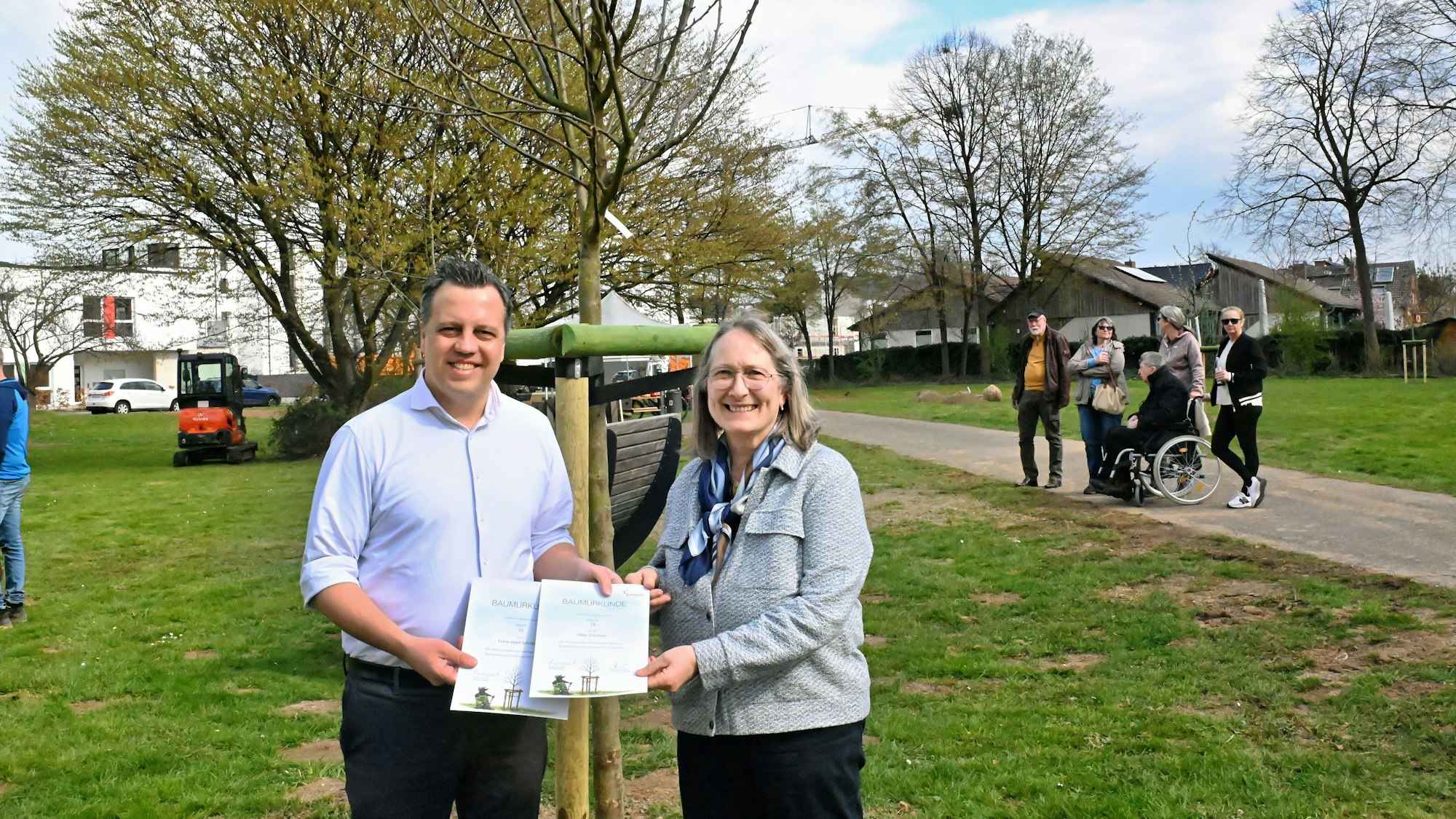 Bürgermeister Sacha Reichelt steht neben Hilde Schröder und präsentiert zwei Urkunden.