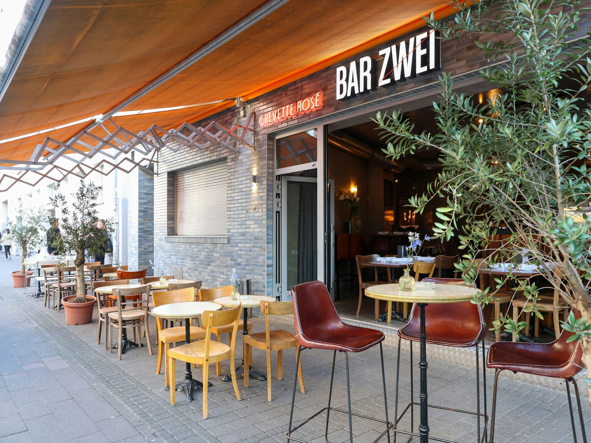 Die Außenansicht zeigt Tische und Stühle auf dem Trottoir.