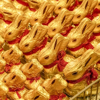 Lindt Goldhasen mit roter Schleife, Schoko-Osterhasen dekorativ aufgereiht.
