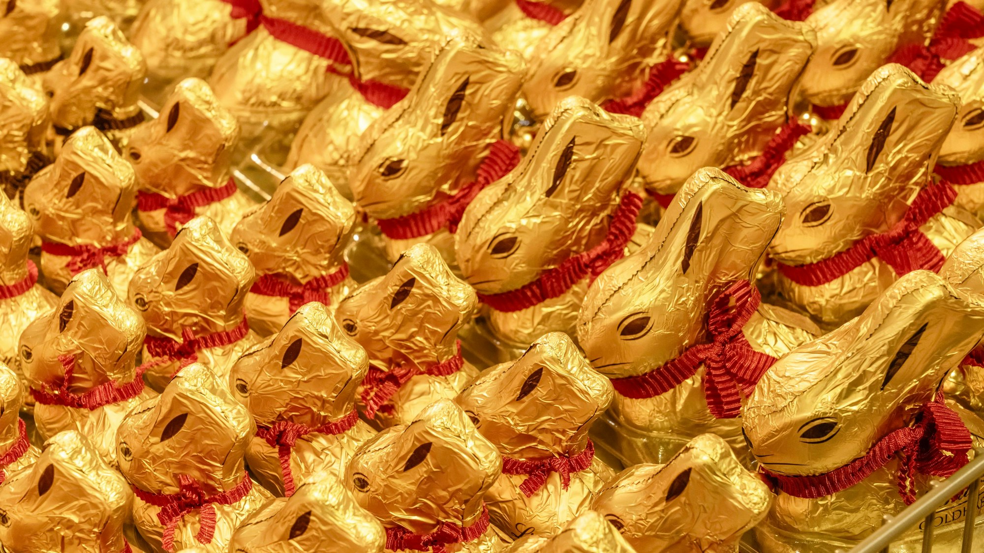Lindt Goldhasen mit roter Schleife, Schoko-Osterhasen dekorativ aufgereiht.