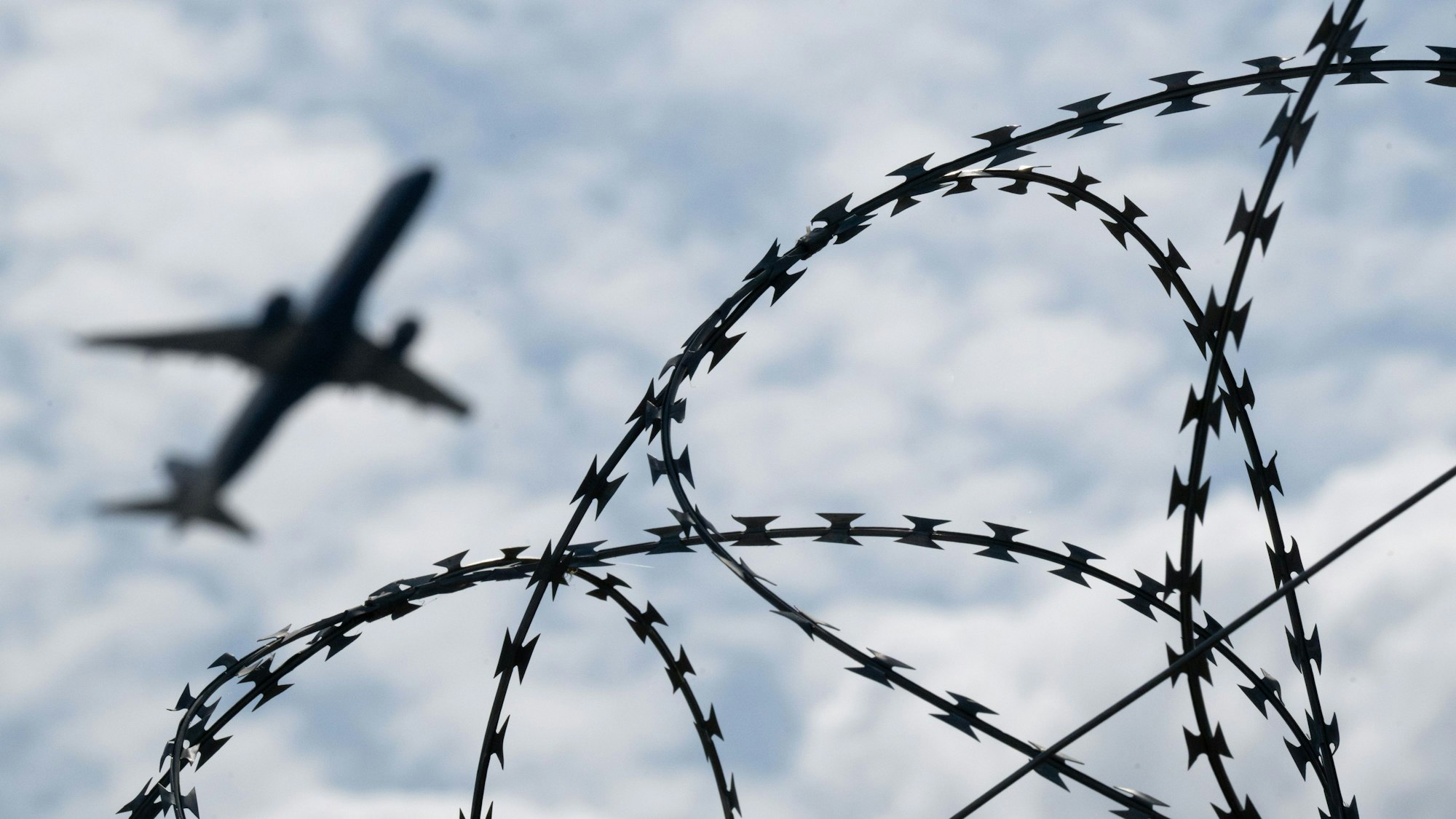 Ein Flugzeug startet hinter einem Zaun mit Natodraht.