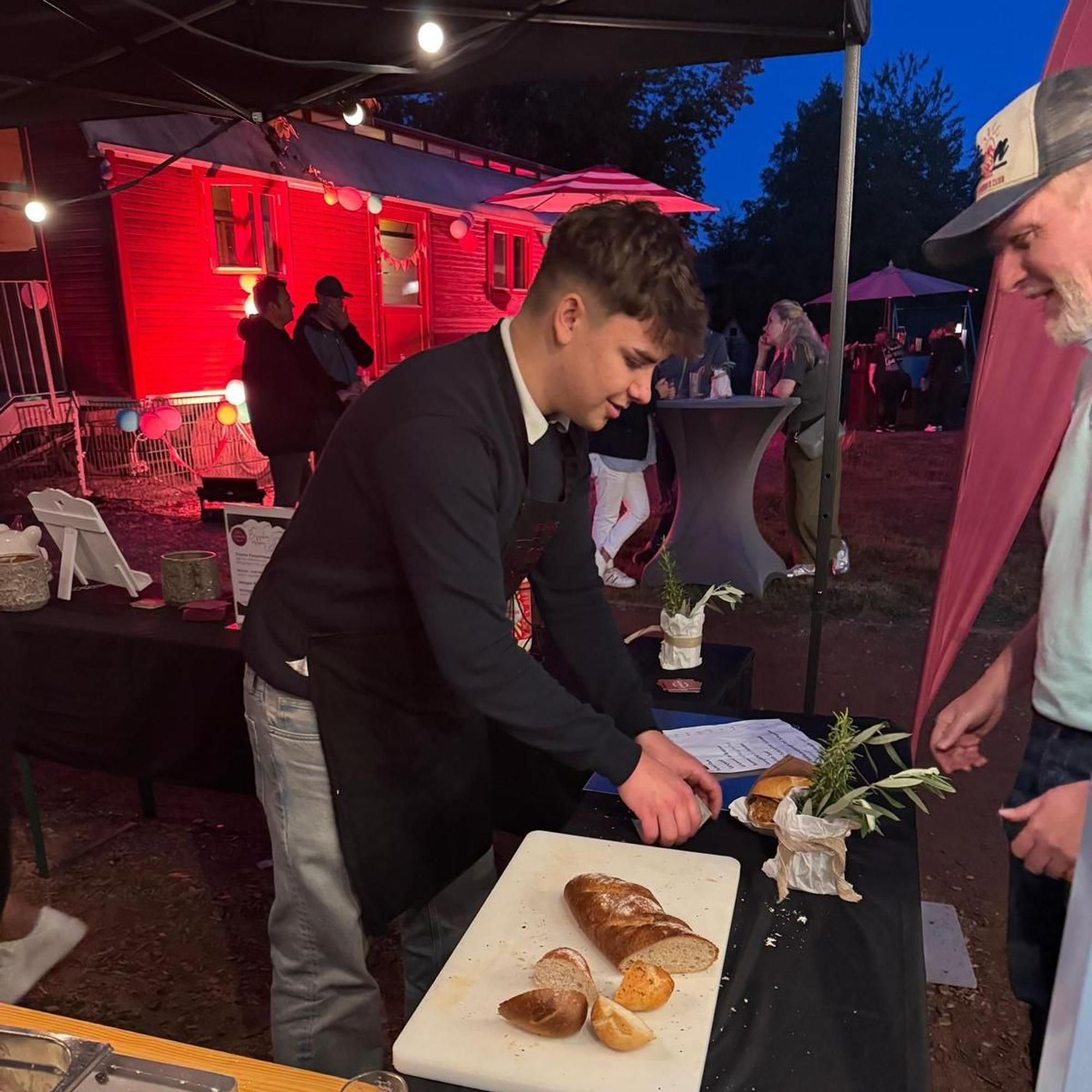 Ein Metzger schneidet bei einem Fest Brot auf.
