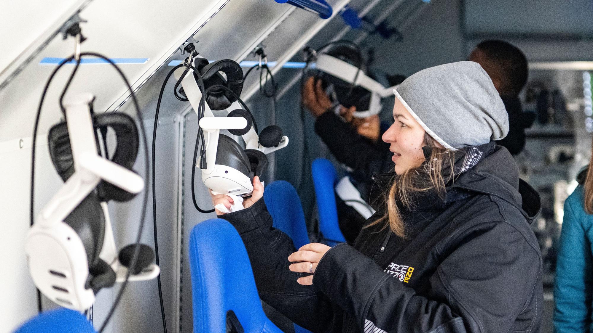 Das Bild zeigt Andrea Schyboll, die gerade eine VR-Brille auf einen Haken hängt.