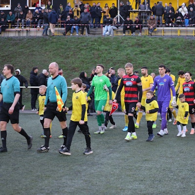 Die beiden Mannschaften laufen mit den Nachwuchskicker ins Achim-Lammers-Stadion in Köttingen ein.