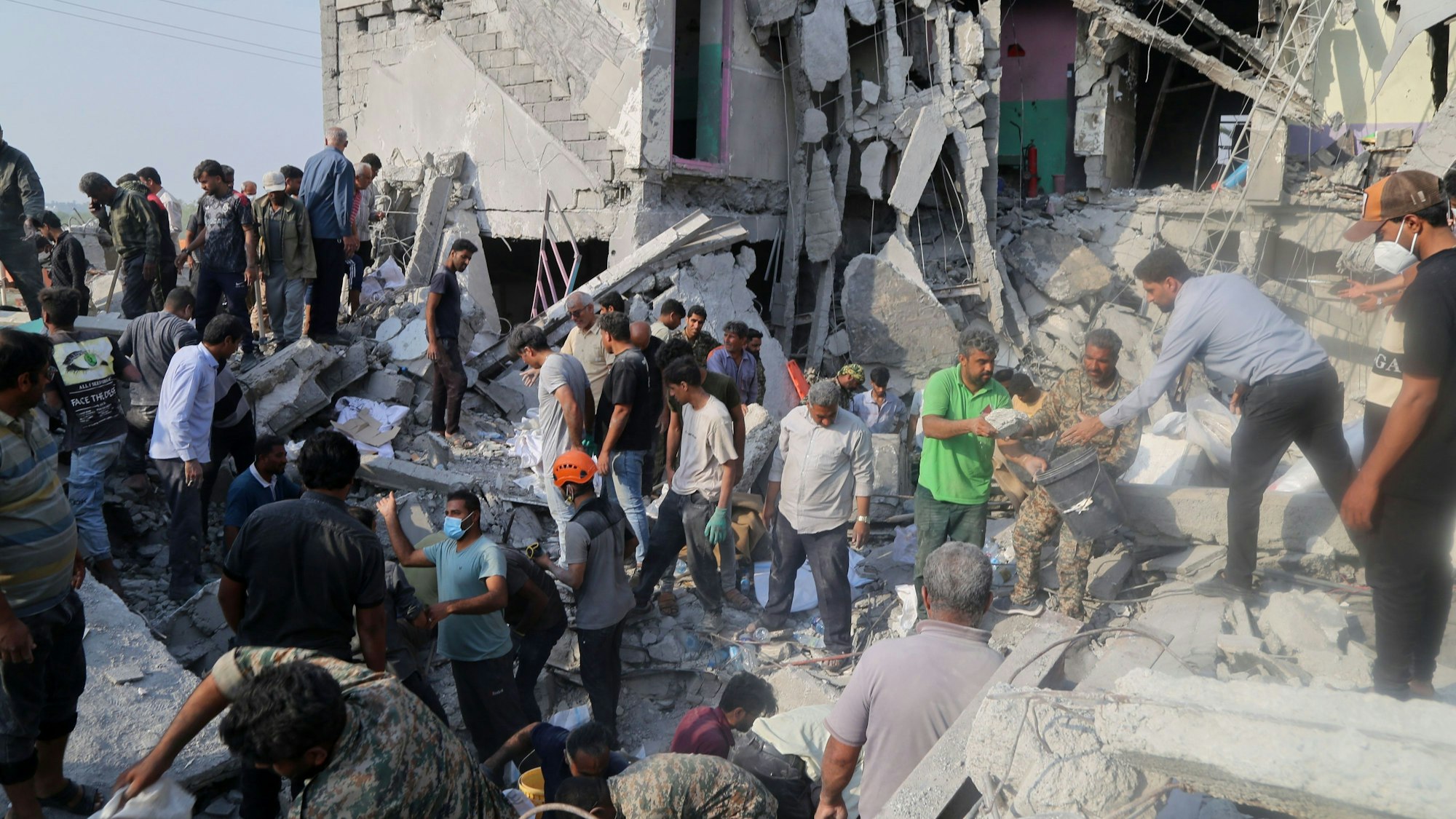 Iran, Minab: Rettungskräfte und Anwohner durchsuchen am 28.2.2026 die Trümmer nach einem Angriff auf eine Grundschule für Mädchen.