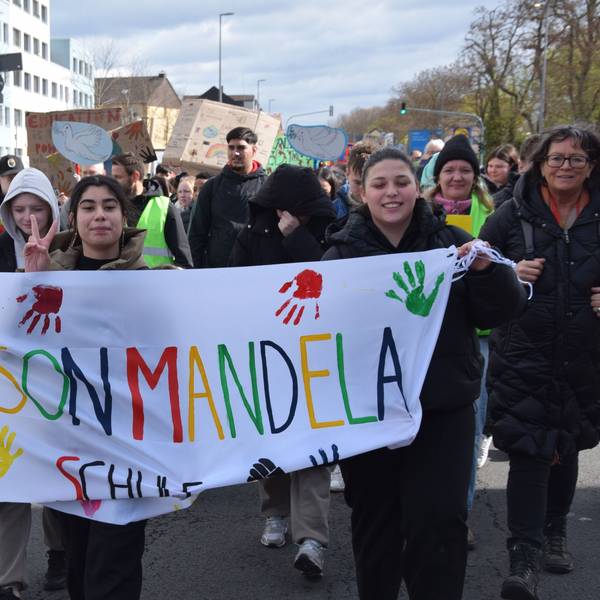 Schülerinnen und Schüler tragen ein Transparent, auf dem Nelson-Mandela-Schule steht.