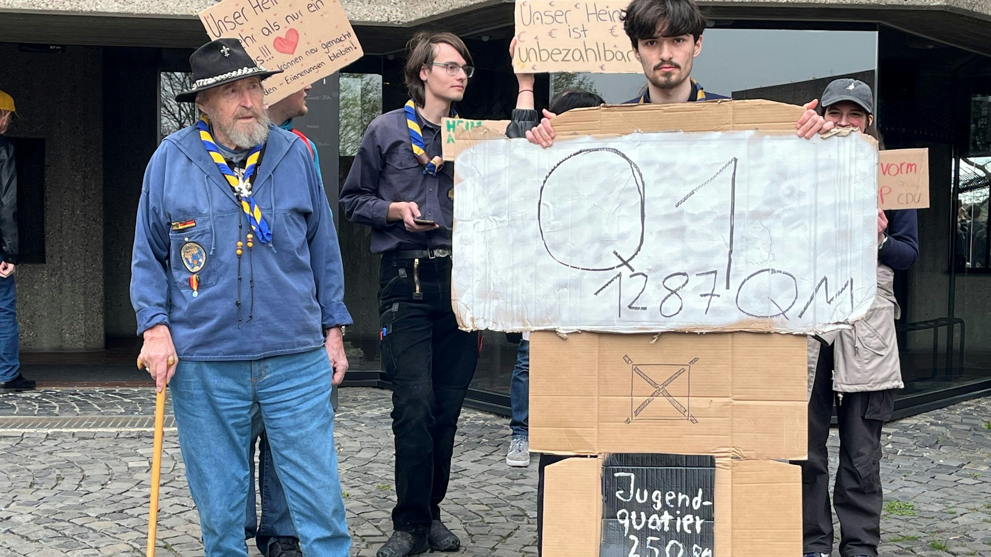 In Pfadfinderkluft steht Mann neben seinen Mitstreitern.