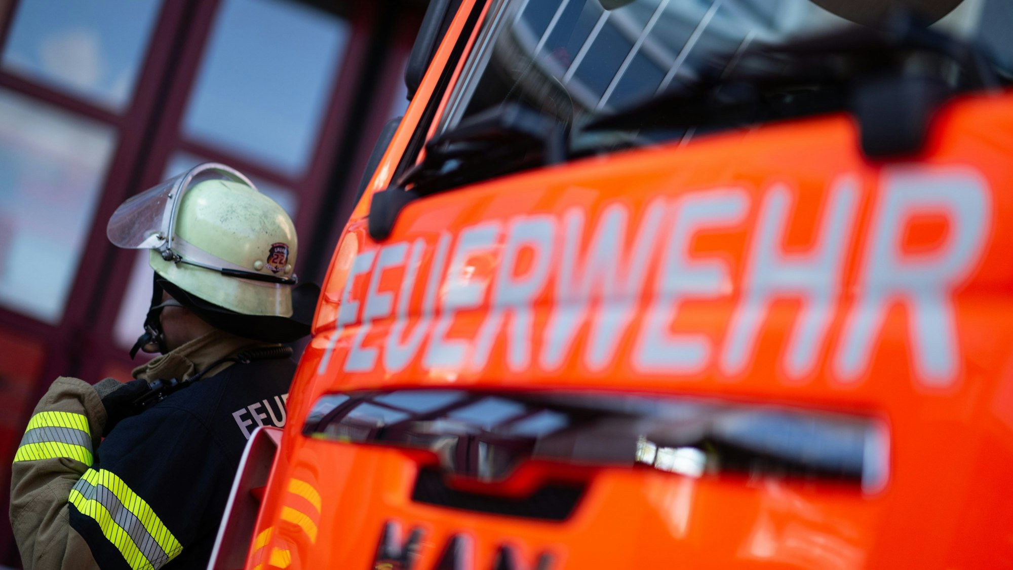 Eine Einsatzkraft der Feuerwehr steht neben einem Einsatzfahrzeug der Feuerwehr. (Symbolbild)