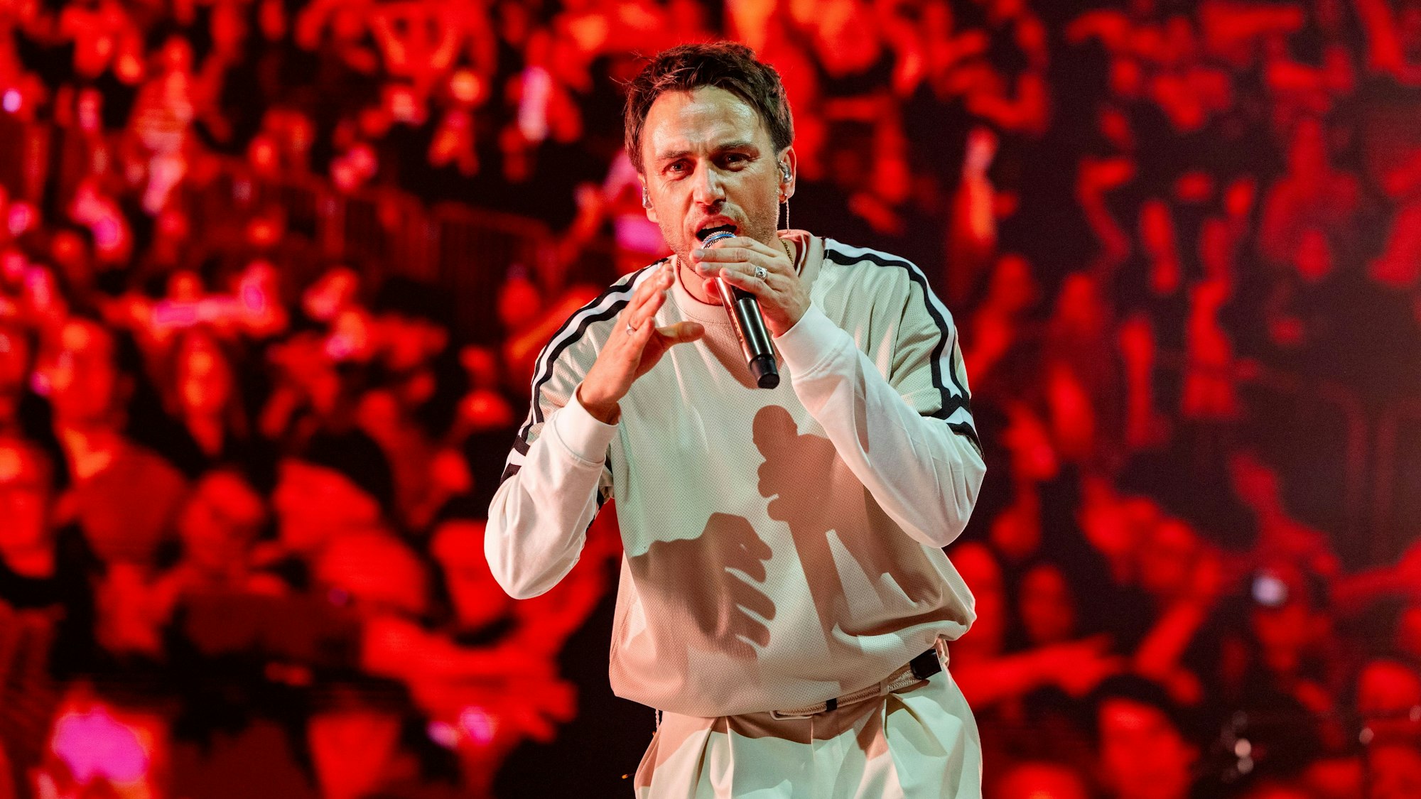 Ein Mann hält ein Mikrofon in der Hand und singt.