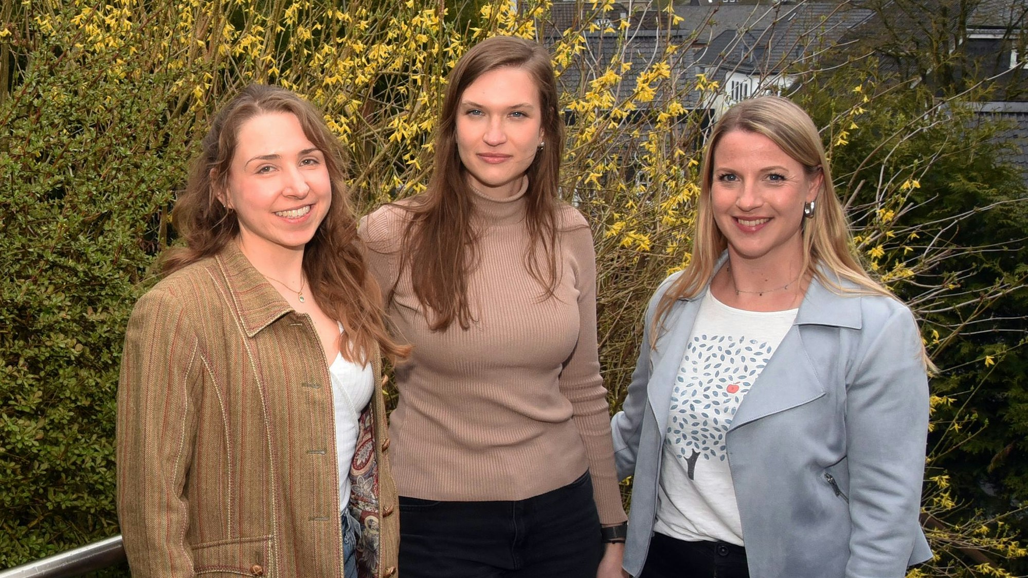 Das Foto zeigt drei Mitarbeiterinnen der Hansestadt Wipperfürth vor einem blühenden Strauch..