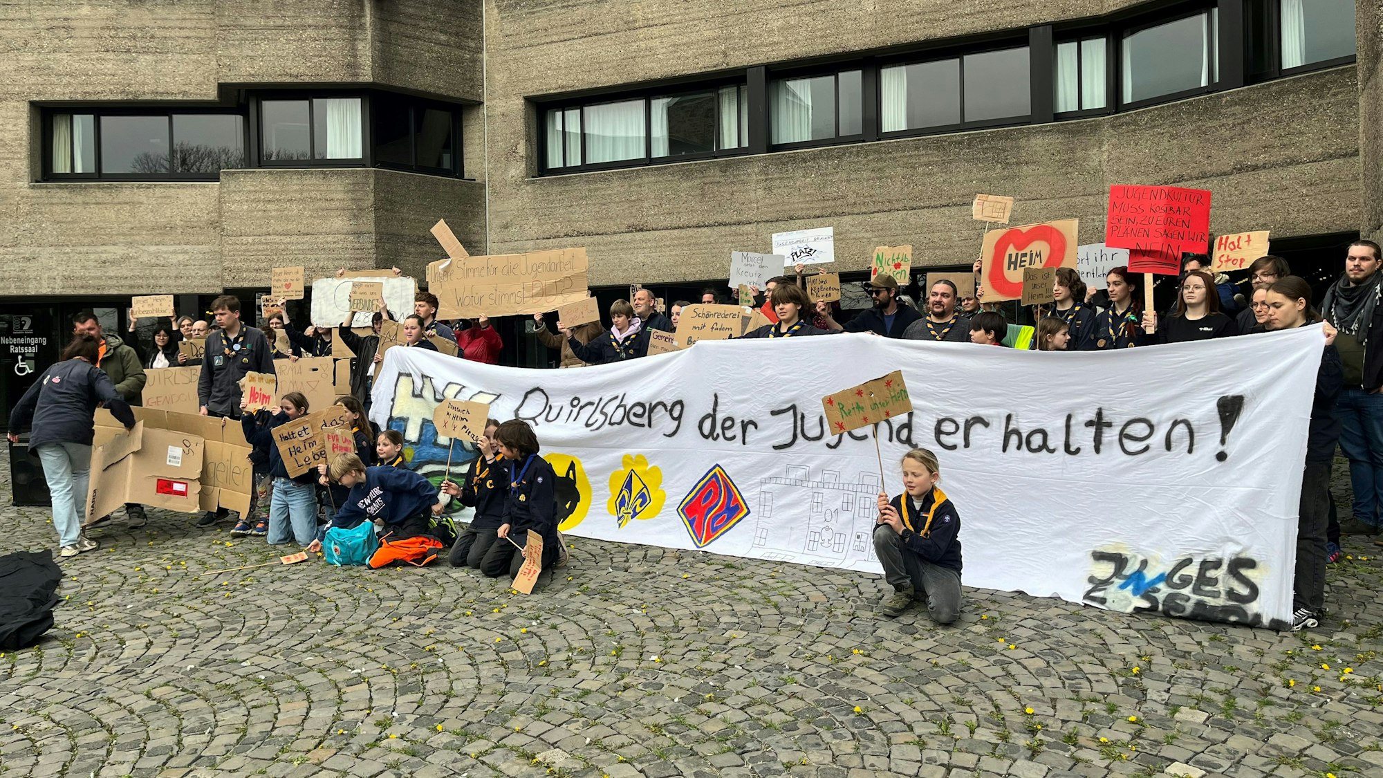 Mit Plakaten und einem großen Transparent stehen die Demonstranten vor dem Eingang zum Rathaus.