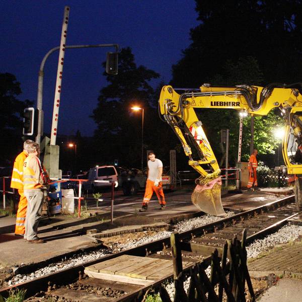 Bahnbauarbeiter arbeiten mit einem Bagger am Bahnübergang Gerottener Weg in Rösrath am Gleis der Regionalbahnstrecke 25.