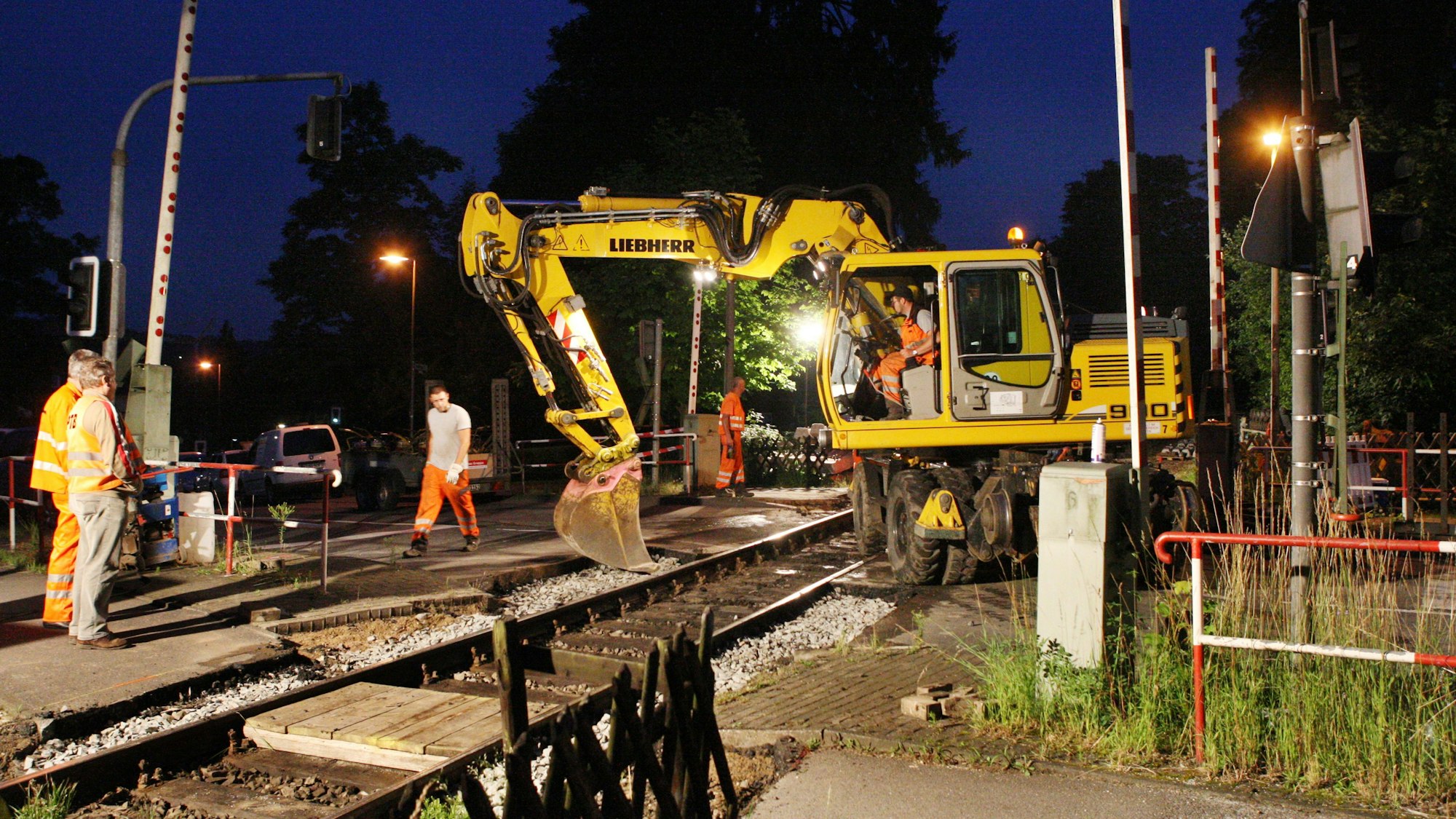 Bahnbauarbeiter arbeiten mit einem Bagger am Bahnübergang Gerottener Weg in Rösrath am Gleis der Regionalbahnstrecke 25.