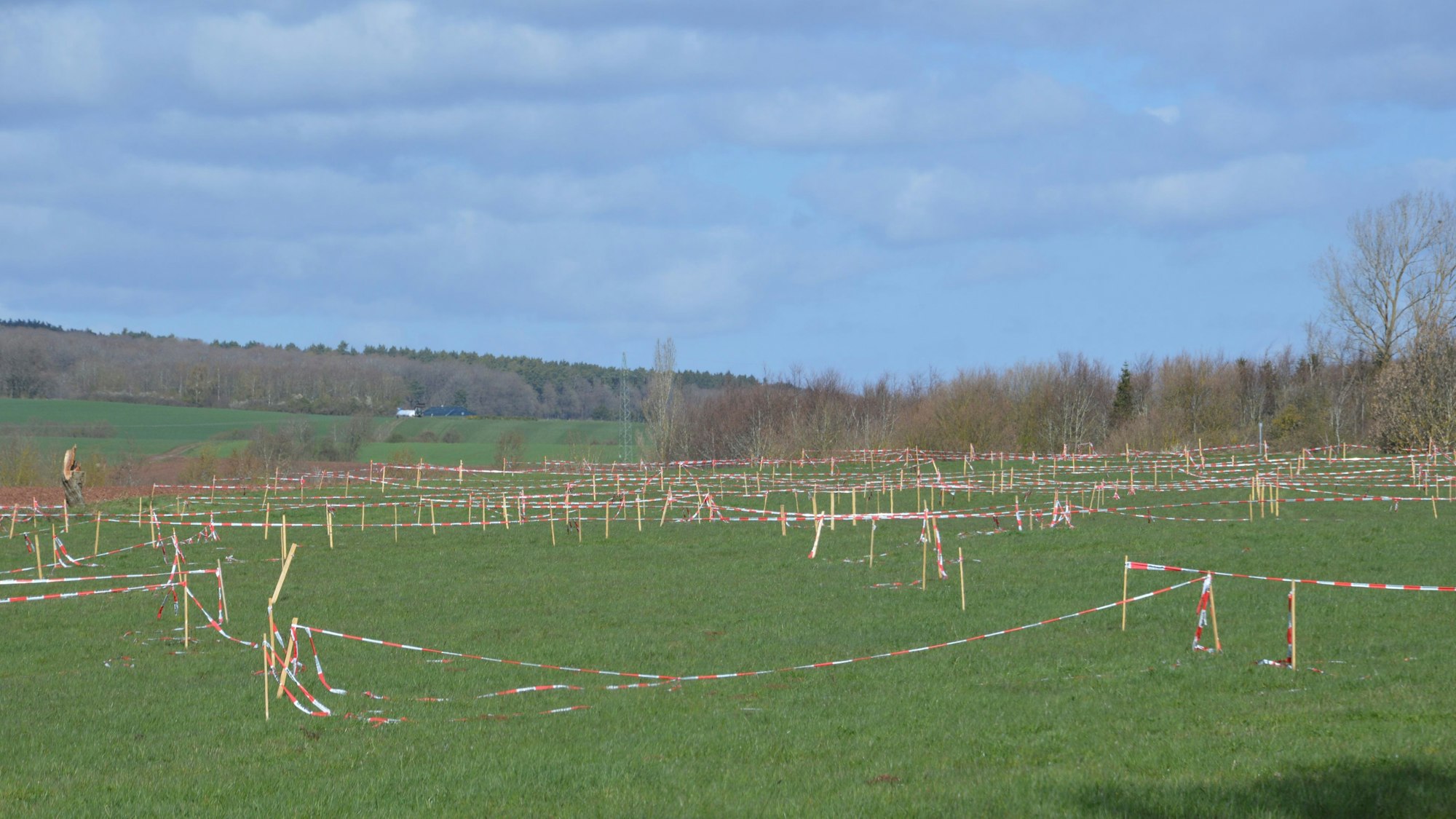 Auf dem Foto sind kleine Holzpfosten zu sehen, an denen Flatterbänder befestigt sind.