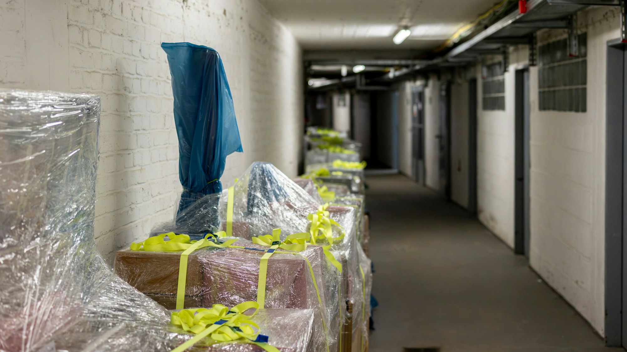 Am Rand eines Flurs stehen Paletten mit Kartons..