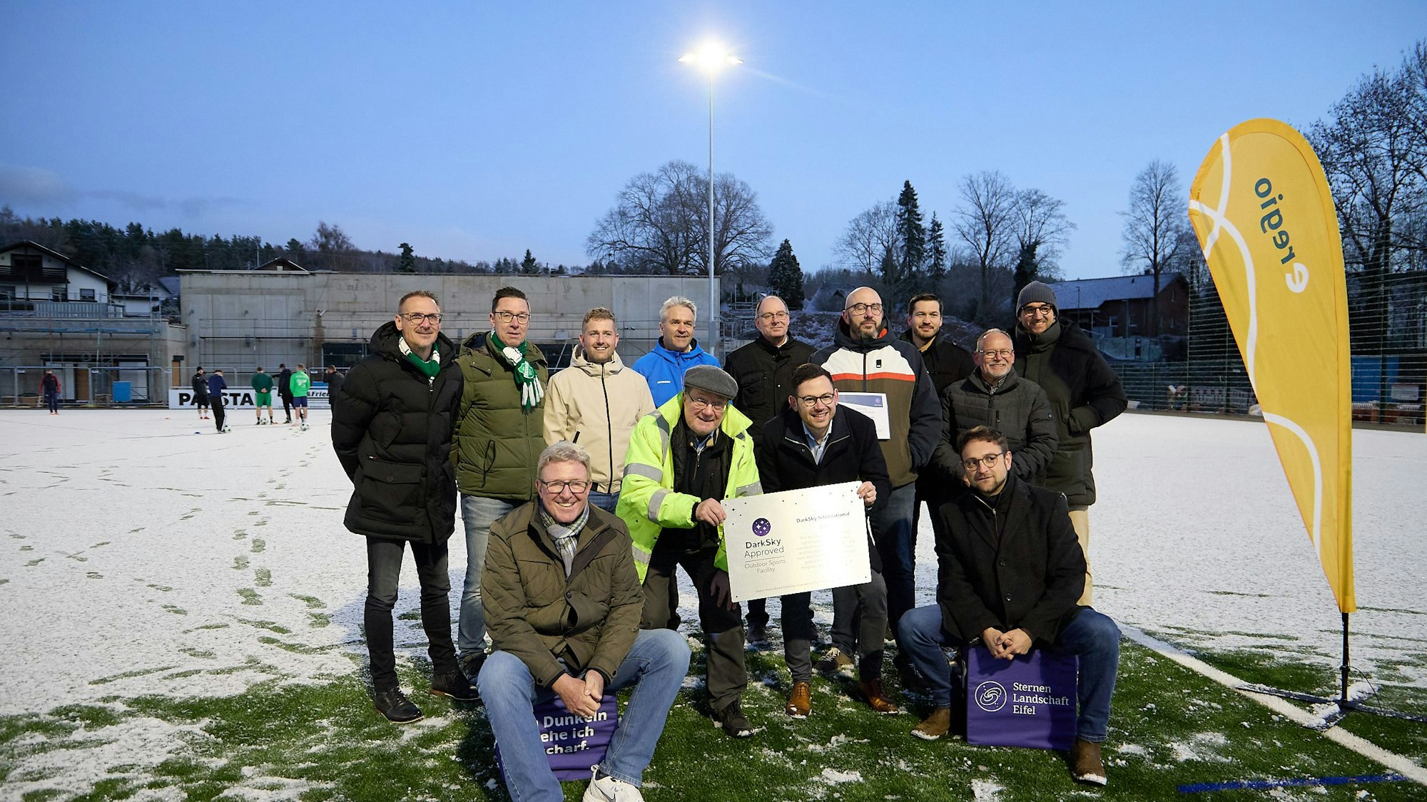 13 Männer stehen und sitzen in nebeneinander auf dem Sportplatz in Kall-Sötenich und präsentieren ein Zertifikat.