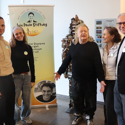 Auf dem Foto ist eine Familie mit dem Künstler HA Schult zu sehen.