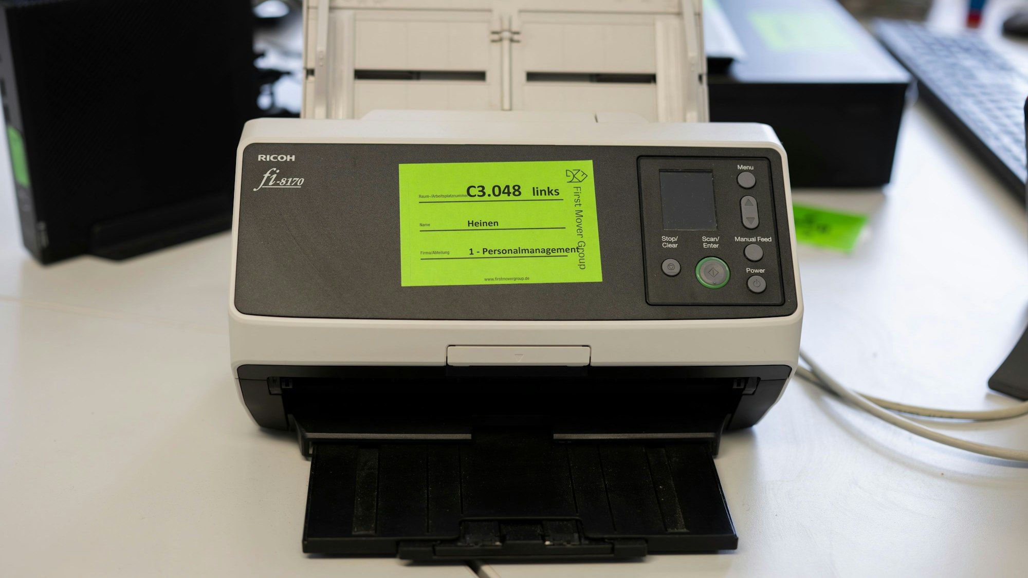 Auf einem Bürogerät ist ein grüner Aufkleber angebracht.