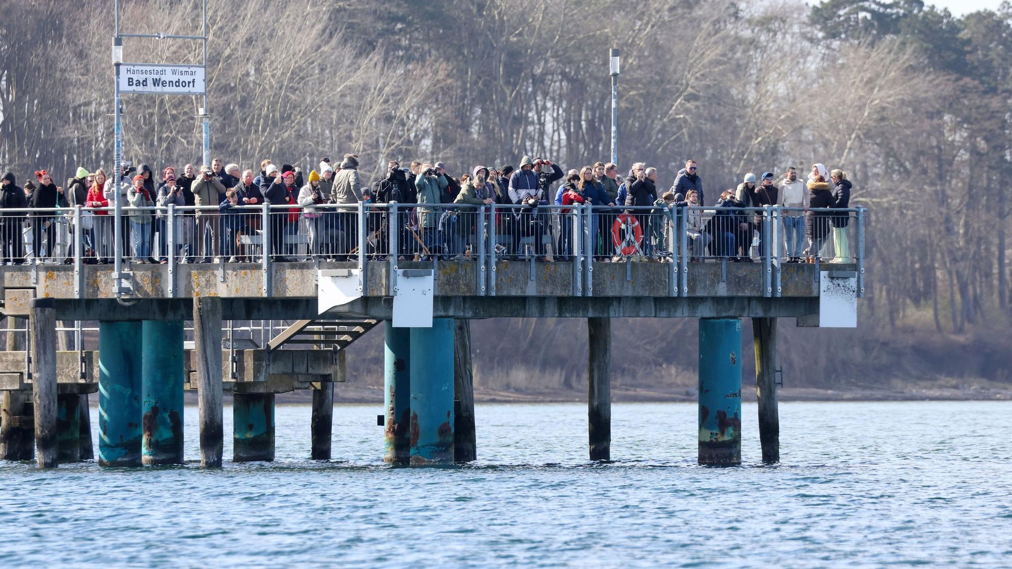 Schaulustige stehen am Sonntagnachmittag auf der Seebrücke in Wismar. Der vor rund einer Woche bei Timmendorfer Strand an der Ostseeküste gestrandete Buckelwal liegt noch immer in der Wismarbucht.