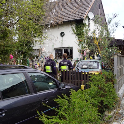 Zwei Polizisten stehen an einem Haus in Euskirchen-Billig, in dem es zu einer Verpuffung gekommen war.