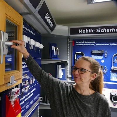 Eine Frau steht vor einem Fenster und berührt den Griff mit ihrer Hand.