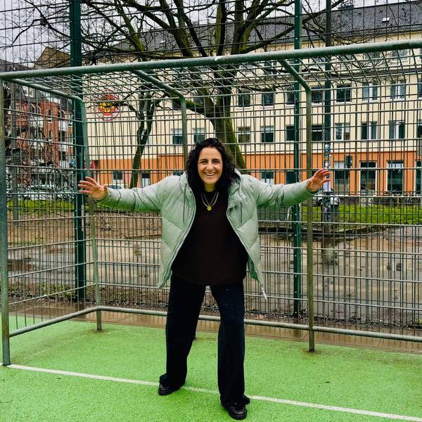 Eine Frau steht vor einem Fußballtor auf einem Bolzplatz.