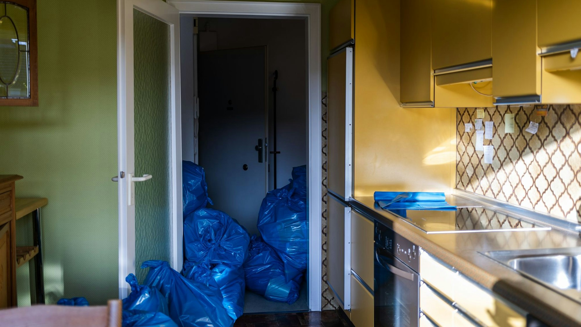 Blick in eine Küche und einen Flur mit vielen blauen Säcken.