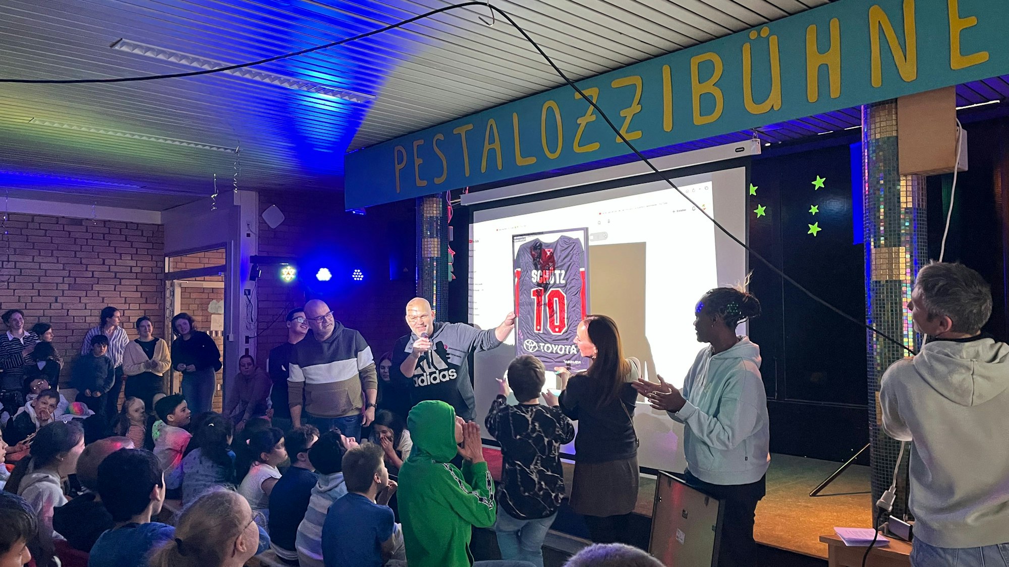 Ein signiertes Trikot der Kölner Haie löst Begeisterung bei den Mädchen und Jungen der Pestalozzischule aus. Die Spende bekamen sie zusätzlich zum Kreativpreis, mit dem ihr Engagement fürs Klima gewürdigt wurde.
