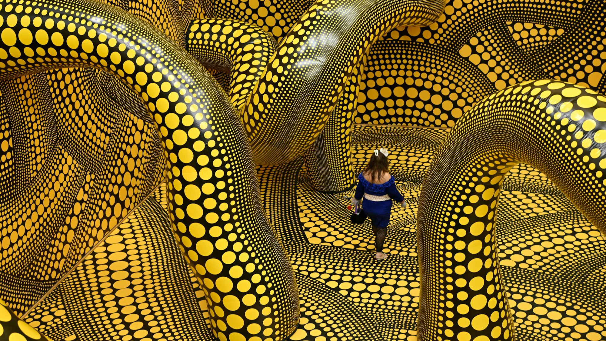 Eine Frau läuft durch die Installation „Infinity Mirrored Room – The Hope of the Polka Dots Buried in Infinity Will Eternally Cover the Universe“ von Yayoi Kusama im Museum Ludwig.