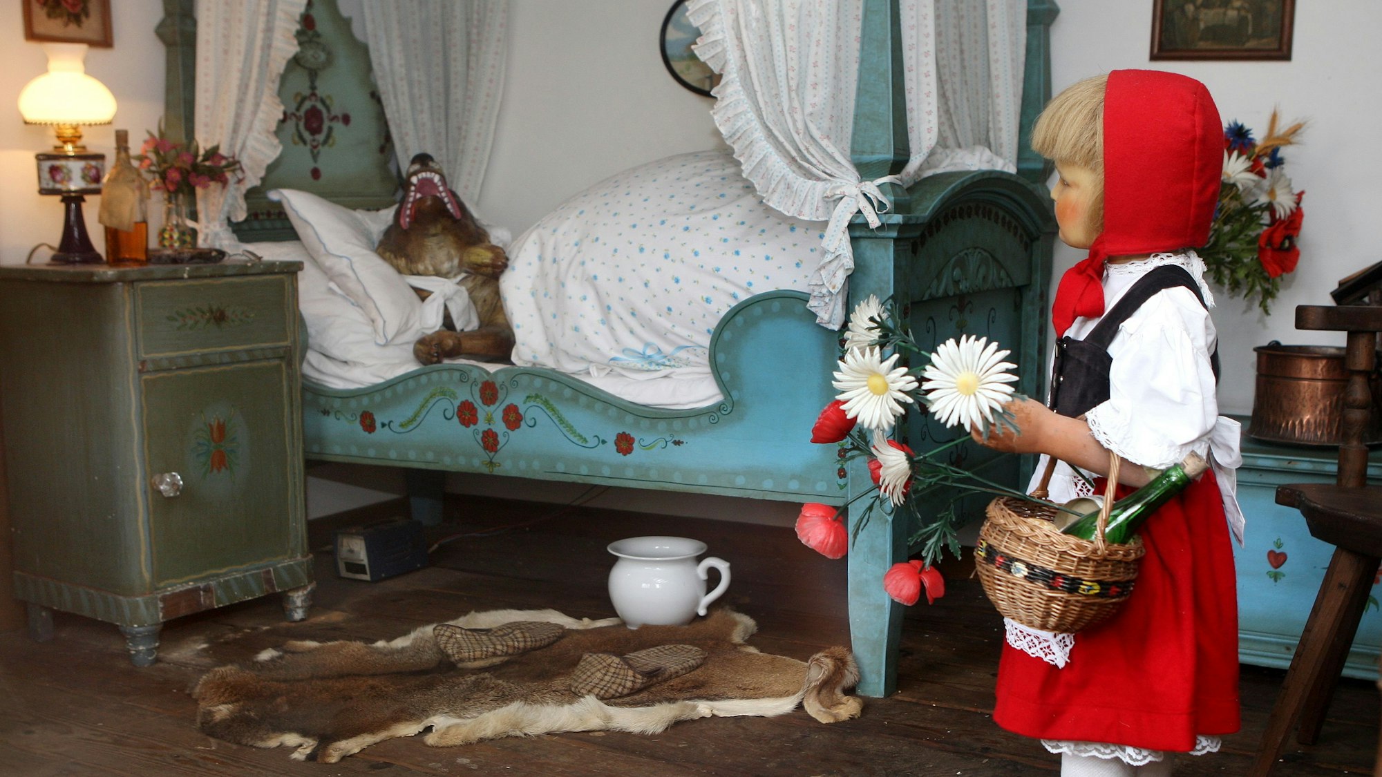 Blick in eines der Märchenhäuser. Gezeigt wird die Szene aus Rotkäppchen, der Wolf liegt verkleidet im Bett der Großmutter.