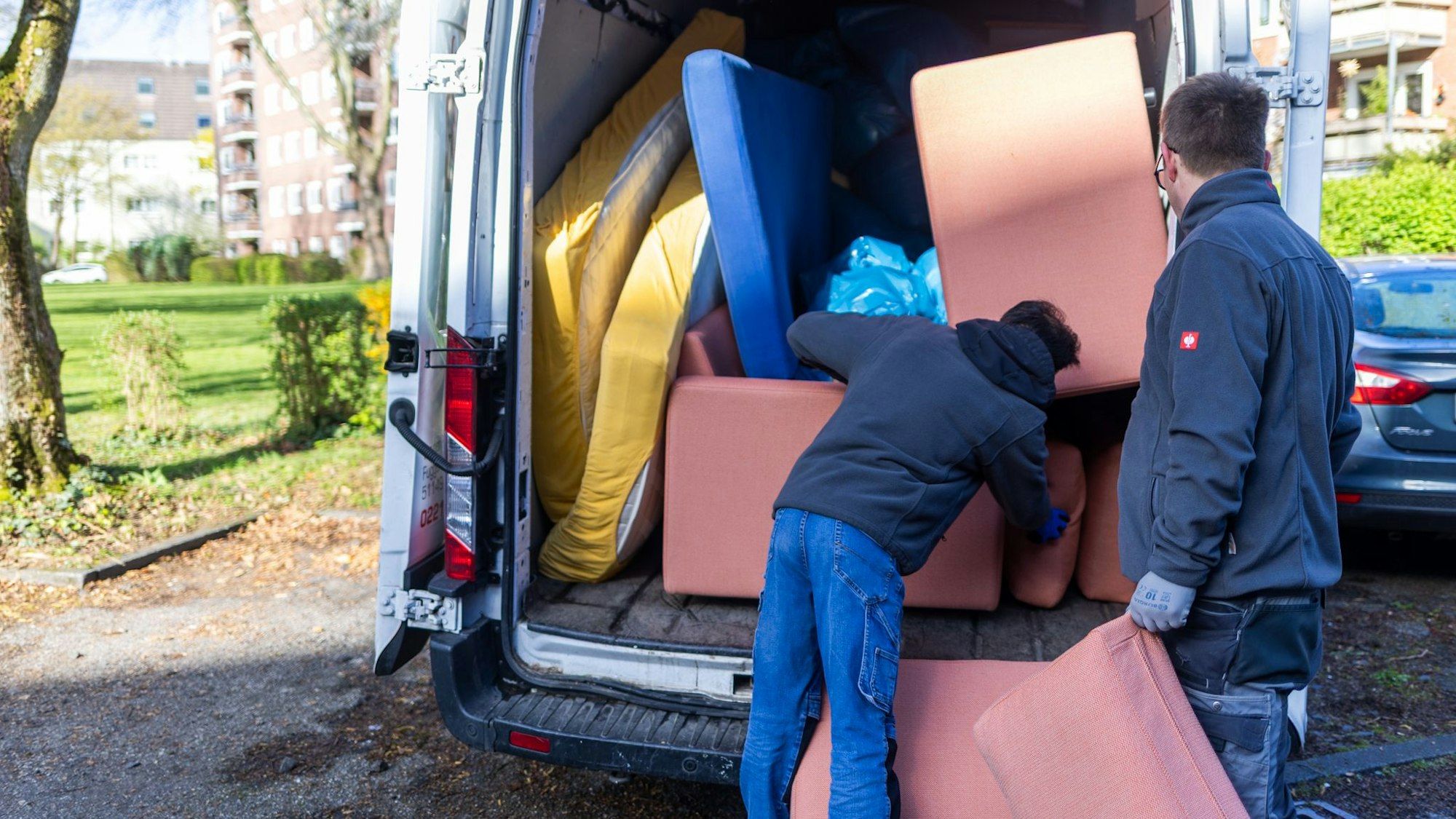 Zwei Männer räumen einen Transporter ein.