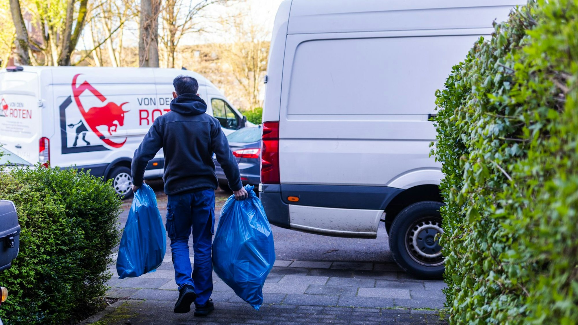 Ein Mann trägt blaue Säcke zu einem Transporter.