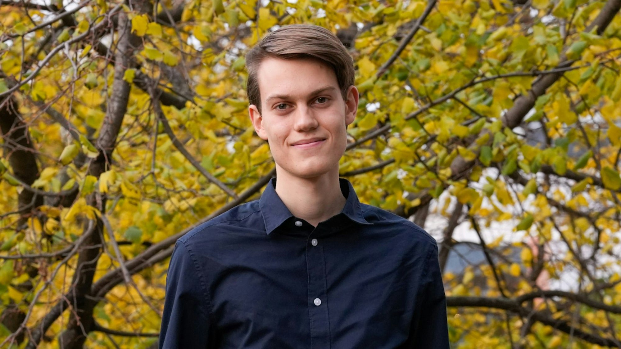 Ein Mann im blauen Hemd lächelt in die Kamera.