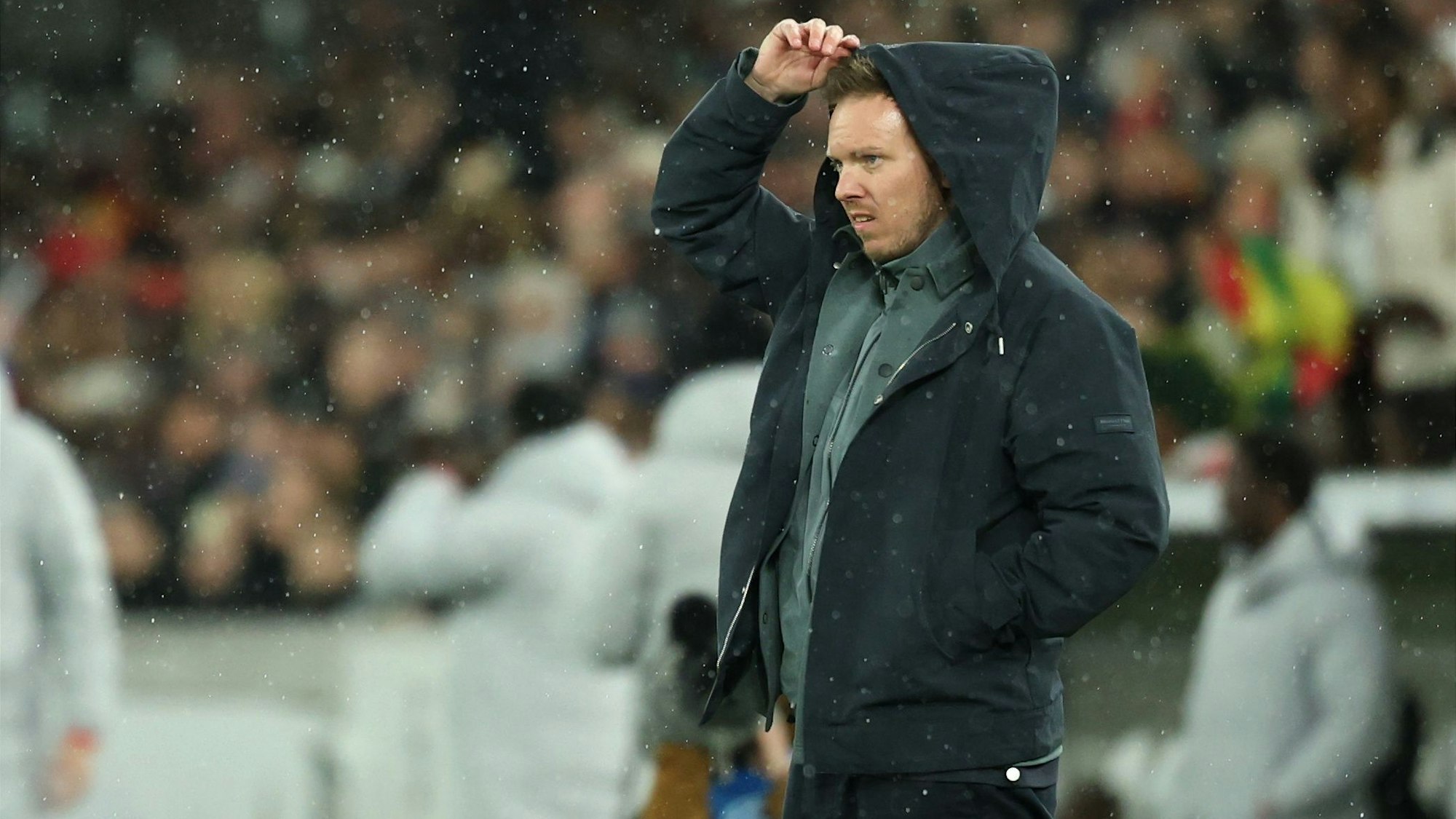 Julian Nagelsmann richtet sich im Regen die Kapuze.
