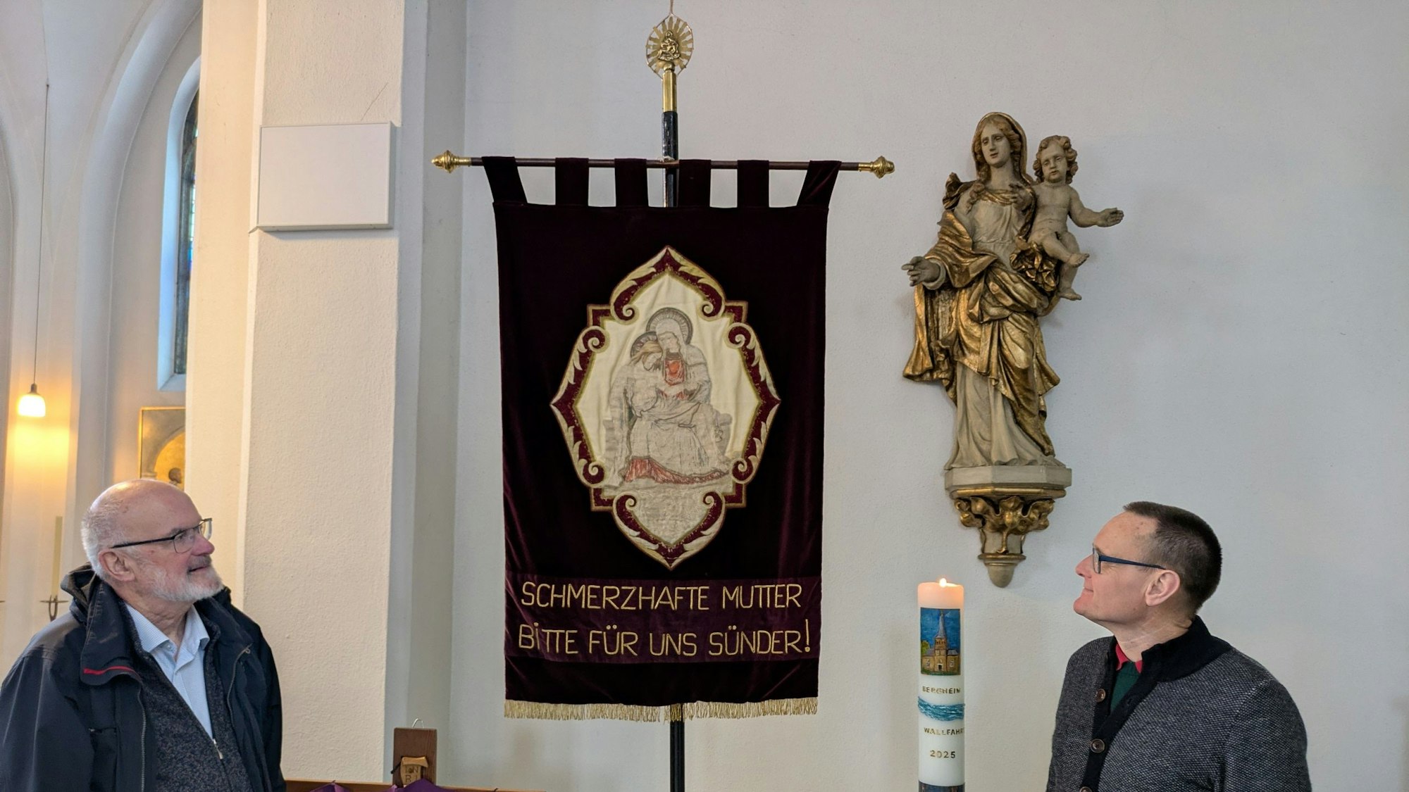 Zwei Männer stehen vor einer Pilgerfahne.