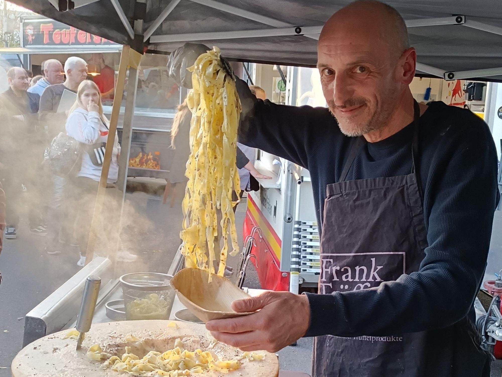 Ein Mann füllt Pasta aus einem Parmesanlaib in eine Schale.