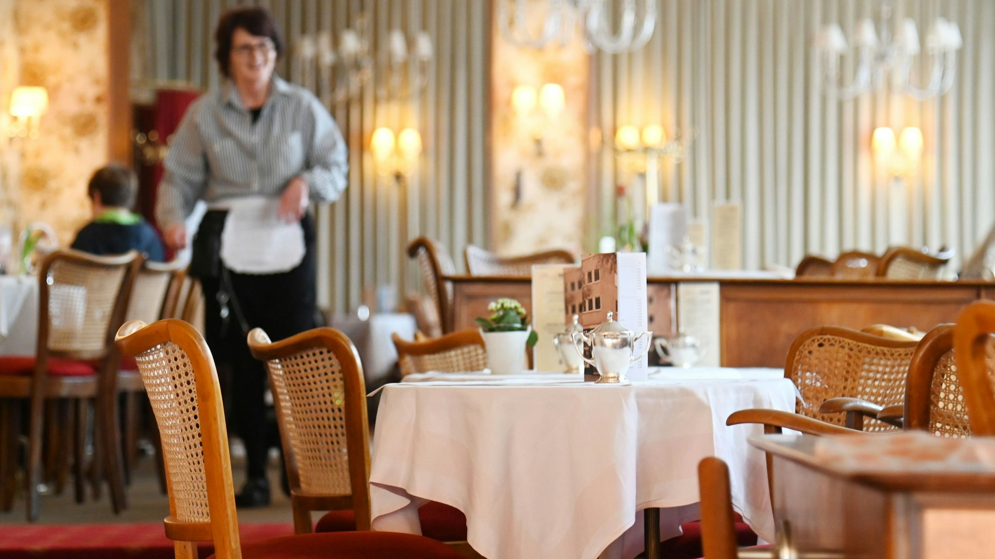 Der Gastraum ist zu sehen mit Jugendstilmobiliar und gedeckten Tischen.