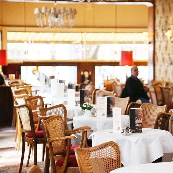 Der Gastraum ist zu sehen mit in Reihe stehenden kleinen runden Café-Tischen.