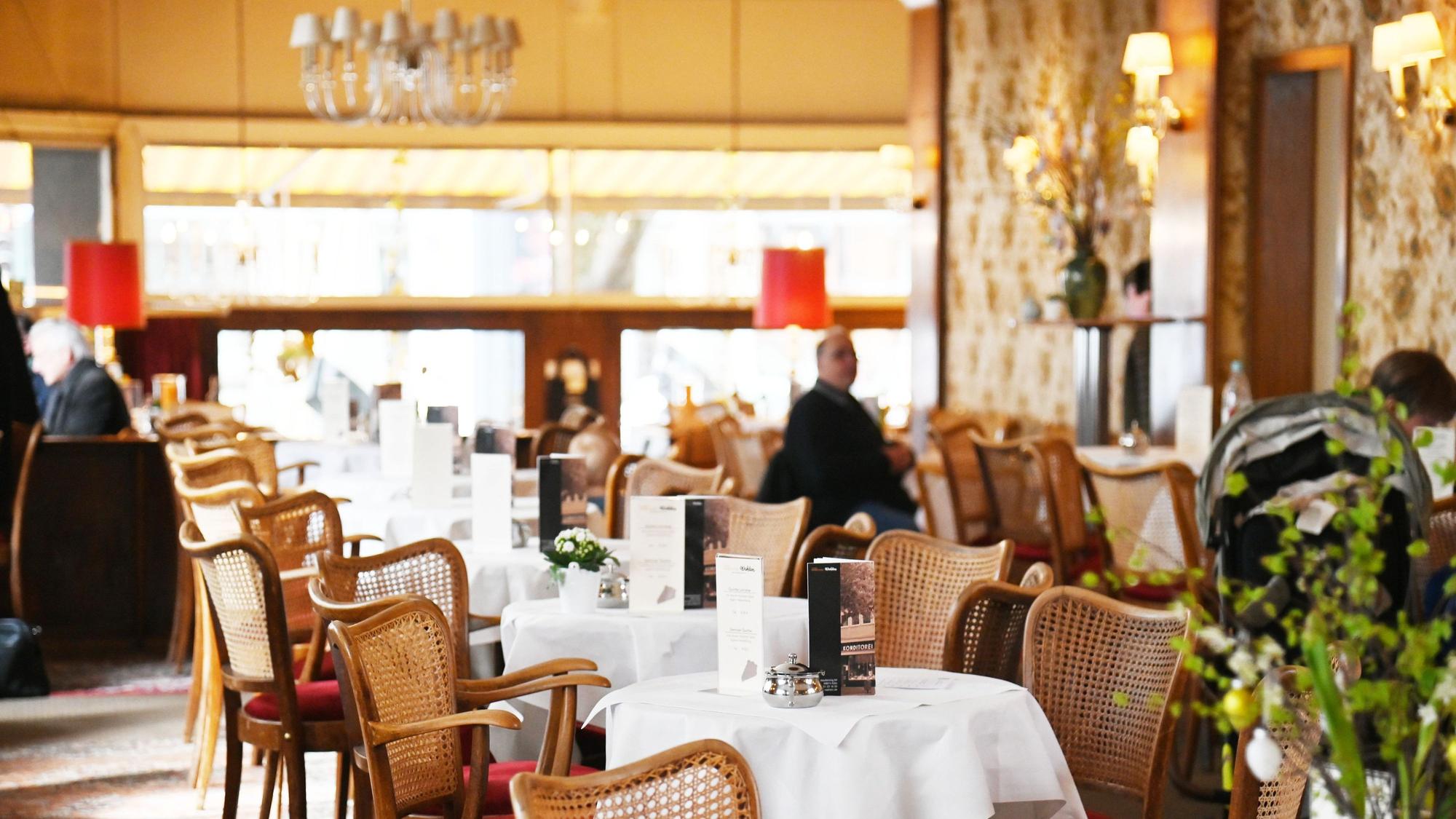 Der Gastraum ist zu sehen mit in Reihe stehenden kleinen runden Café-Tischen.
